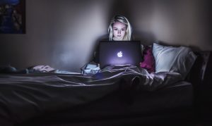 Woman in bed with an Apple MacBook laptop