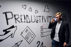 Man standing in front of a wall labelled 'Productivity.' 